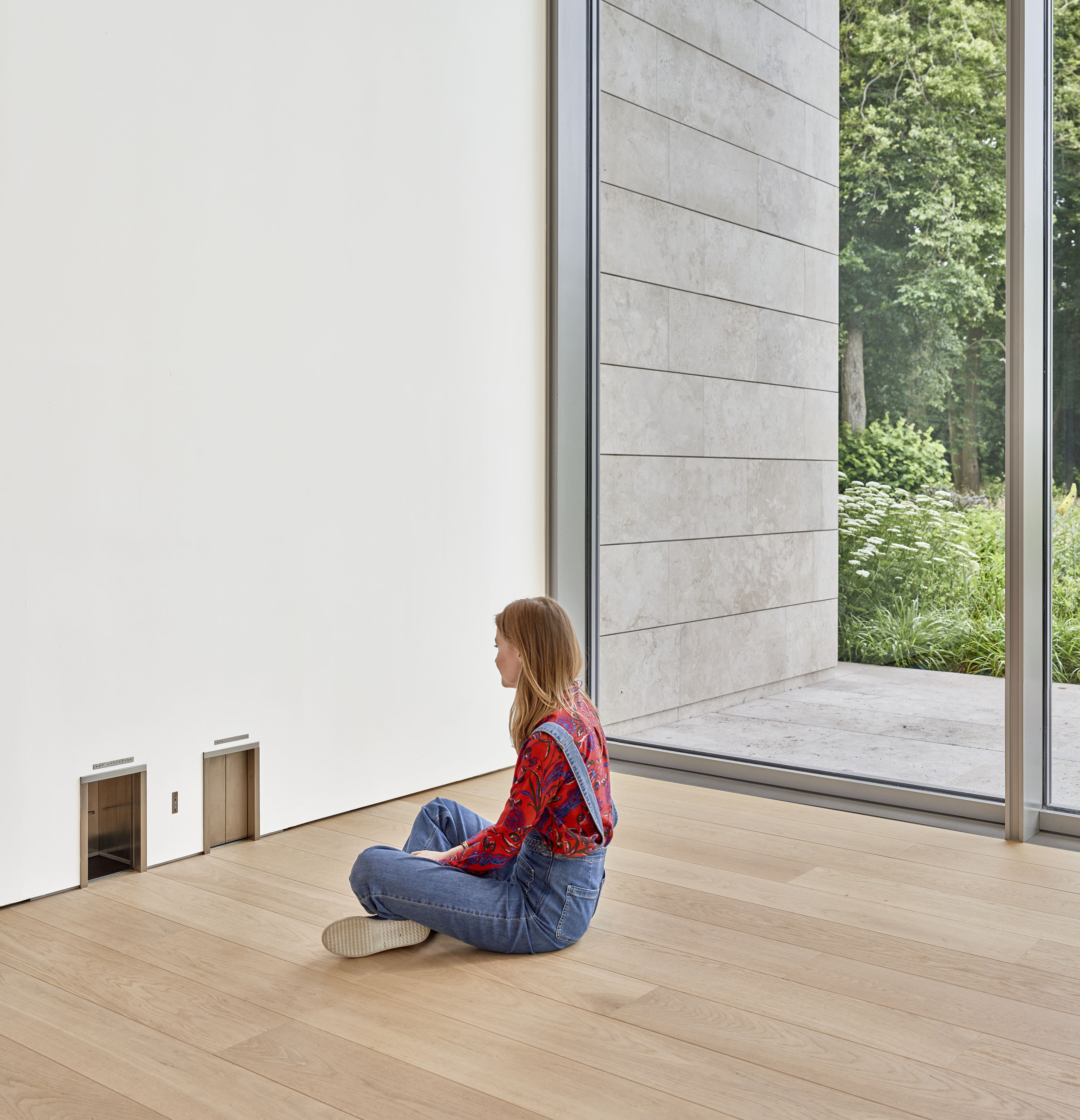 Vrouw zit voor miniliftjes Maurizio Cattelan in museum Voorlinden 